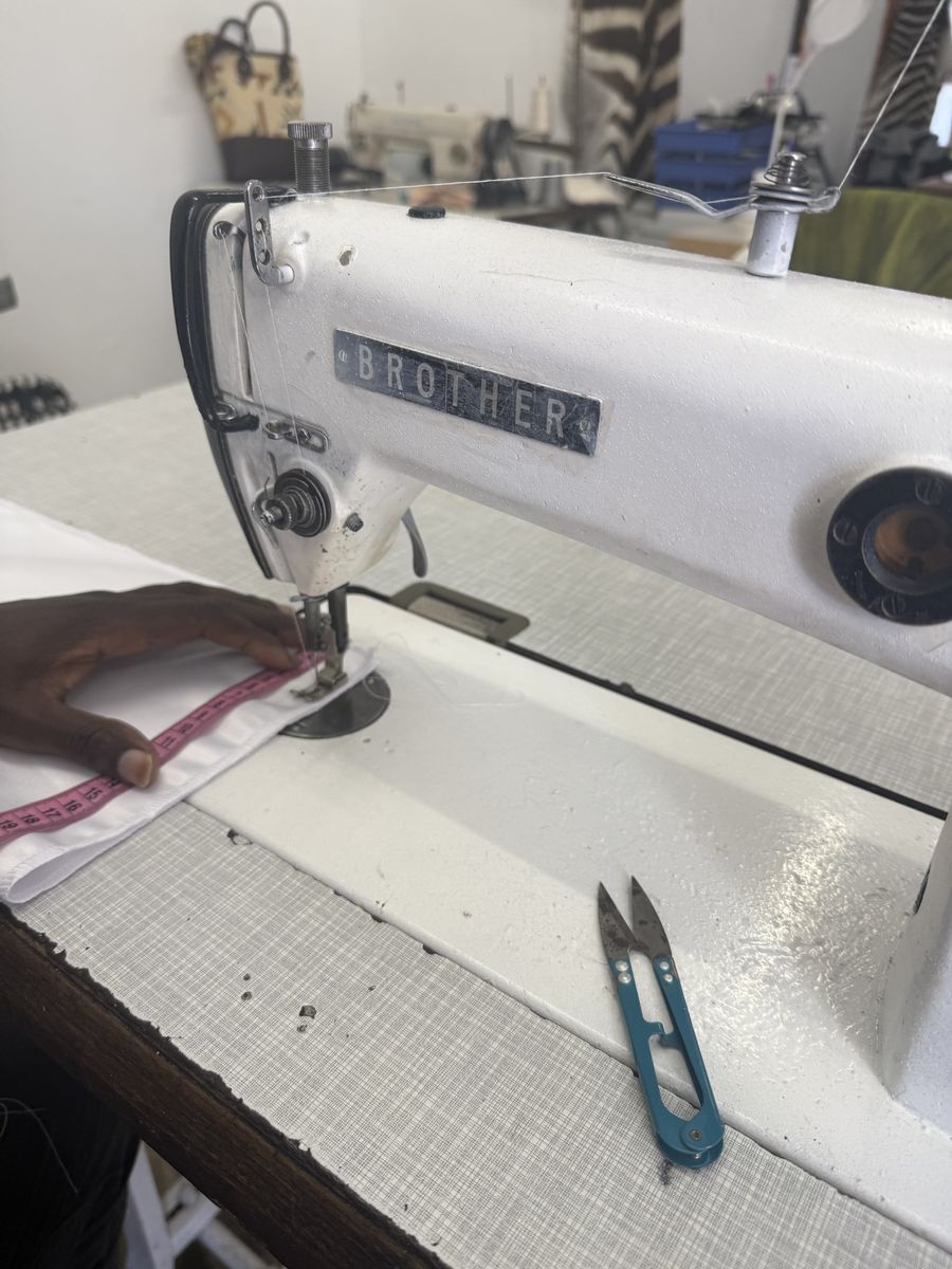 Machinist sewing a garment on an industrial Brother machine at Eli & Co