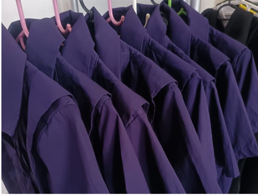 A small batch of uniform shirts on the rail